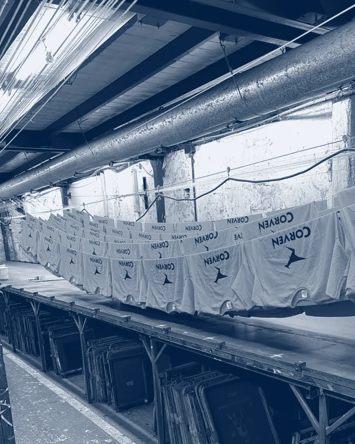 Camisetas naranjas colgadas después del secado, con las pantallas de serigrafía abajo