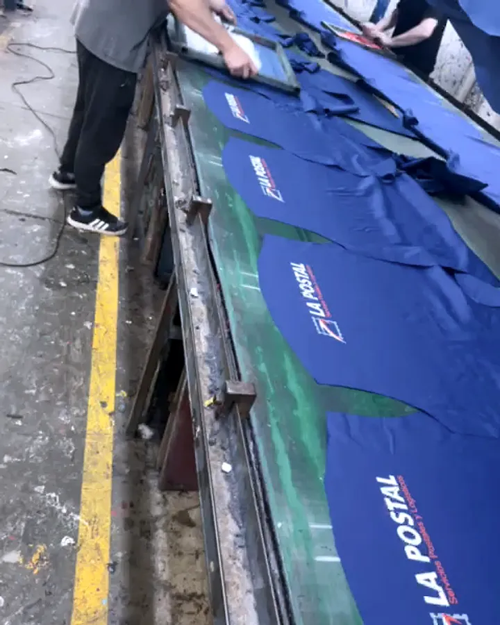 Remeras azules con logo en la espalda, serigrafía en mesa, empresa